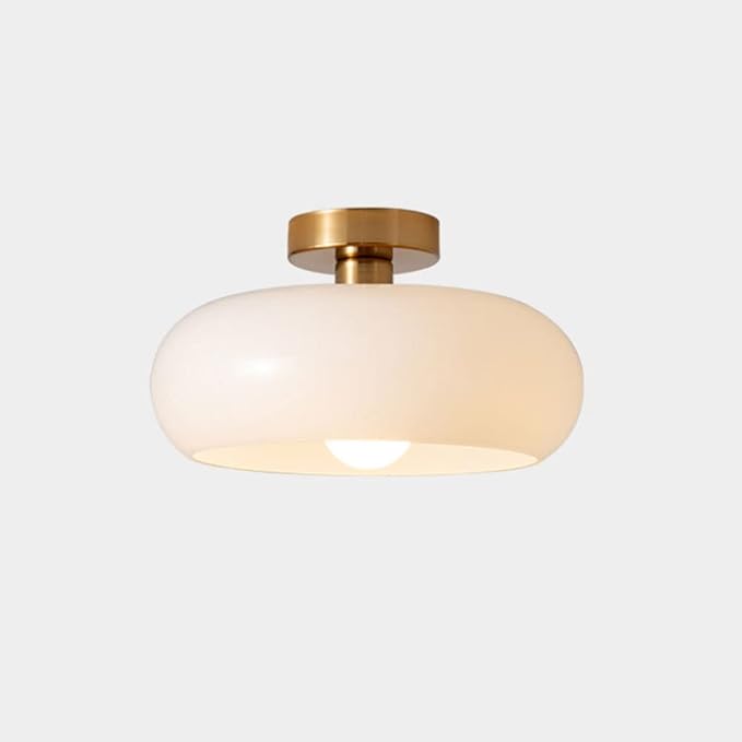 Ceiling light fixture with gold finish and white glass shade on a light gray background