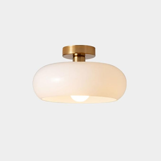 Ceiling light fixture with gold finish and white glass shade on a light gray background